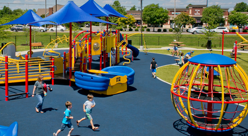 Commercial inclusive playground design featuring integrated shade structures, multi-level play systems, and rubberized safety flooring.