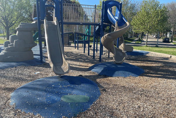 Durable commercial playground slides with integrated rubber safety surfacing and fall protection wear mats.