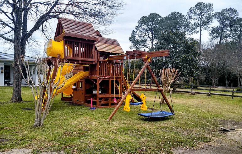 Custom residential wooden playground with clubhouse, tube slide, and heavy-duty swing set for backyards.